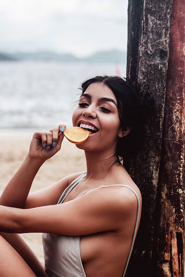 Woman enjoying an orange beside the water